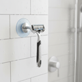 Suction cup hook holding a razor on a clean shower wall in a modern bathroom